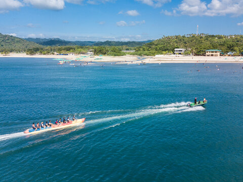 Aerial of a speedboat towing a banana boat near the beach. In Laiya, San Juan, Batangas, Phillipines.
