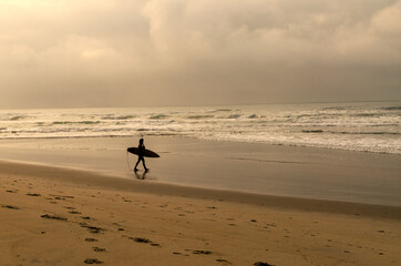 silhouette surfer walking on the sand beach