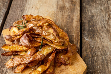 Potato peel chips close-up, wooden background.