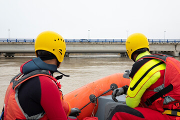 two rescuers observe the river from the boat