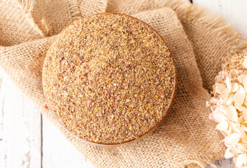 Dried ground flaxseed in a wooden bowl. View from above. Healthy superfood. Close-up.