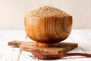 Dry ground flax seeds in a wooden bowl, close-up.