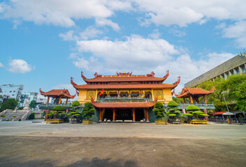 Fototapeta premium Quoc Tu Pagoda in Vietnam, Ho Chi Minh.Red tall asian temple on the blue sky background in Saigon. It is a famous pagoda in Ho Chi Minh city. Travel and religion concept.
