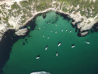 Aerial panoramic view of seascape with crystal clear azure sea and rocky shores. Yachts in a beautiful lagoon on backdrop of rocks. The concept of an ideal destination for summer travel and vacation.