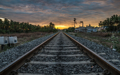 Fototapeta na wymiar Sunrise on a Railway track against sunny sky beautiful clouds.