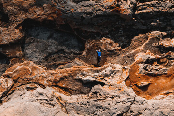 Runner in sport clothes laying on stone texture. Aerial view to caucasian man on rock