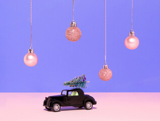 Classic black car with Christmas tree on the roof and pink Christmas baubles decoration on purple background. Pastel purple aesthetic. Happy New year concept.
