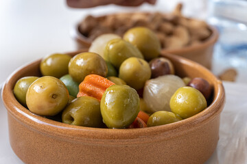Clay bowl with olives and pickled vegetables.