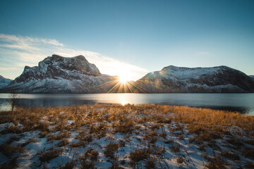 Sunrise rising from behind two snowy rocky mountains. The landscape is going into hibernation in...