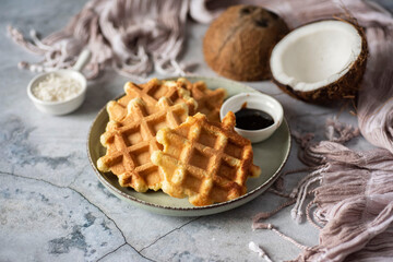 Healthy dessert: coconut waffles on a gray plate on a gray background. Thick waffles made of...