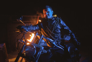 Motorbiker in the blue light on the burning fire background.