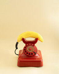retro red telephone with yellow fresh banana imitating phone handset.aesthetic still...