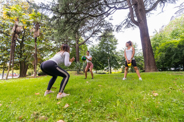 Latin girl doing exercise and sport in a green park, instructor teaching the students in a set of weights