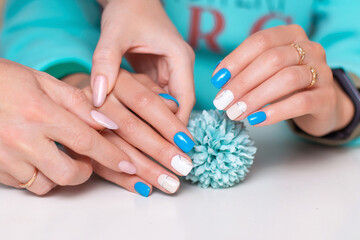 Fototapeta premium Manicurist holding female hands with romantic manicure nails, white and blue gel polish
