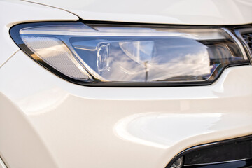 Detail of the right headlight of a new white car
