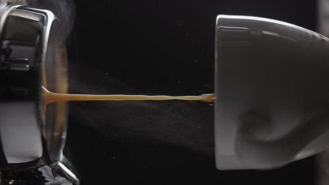 Vertical slow motion pull espresso shot with bottomless portafilter on a professional coffee machine
