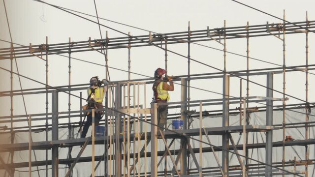 Dangerous work for pair of engineer contractors using welding torch power tools to repair high voltage transformer station after ransomware attack to shut down electrical power grid ma