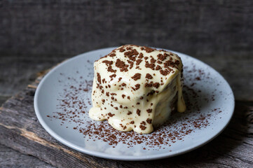 Tiramisu, traditional italian dessert on white plate, wooden background. Selective focus