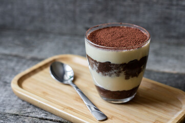 Tiramisu, traditional italian dessert in glass on wooden background. Selective focus