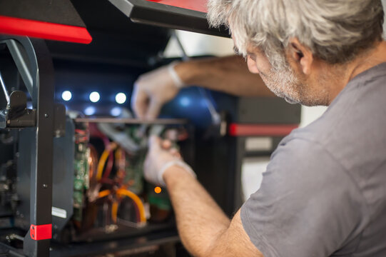 Closeup view of electrical engineer operator repairs industrial printer plotter