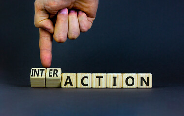 Action or interaction symbol. Businessman turns wooden cubes and changes the word action to interaction. Beautiful grey background, copy space. Business and action or interaction concept.