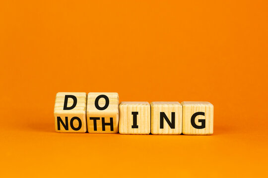 Doing or nothing symbol. Wooden cubes with changed the concept word Nothing to Doing. Beautiful orange table, orange background, copy space. Business, doing or nothing concept.