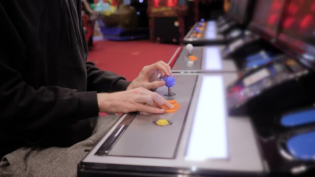 Man hands playing retro arcade machine game and pushing orange buttons. Gaming, 80s, hobby, vintage, technology, retro video game and leisure time concept