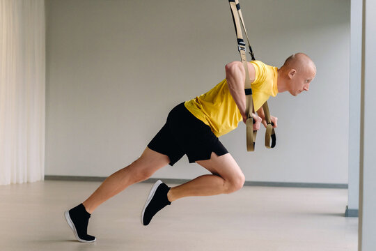 A focused male athlete performing an exercise on functional loops in the gym