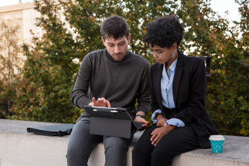 Obraz premium Businessman and businesswoman using a tablet on the street.