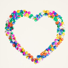 Heart symbol made of flower shaped glitter on white background. Love valentines or woman's day concept. Minimal flat lay.