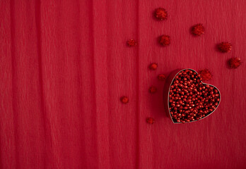 Creative layout with red heart  and pompoms on red background. Nature flat lay. Minimal love concept.