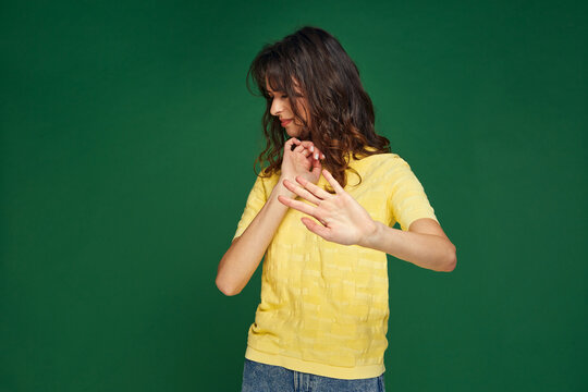 Displeased young girl doing stop gesture turn away from something disgusting unpleasant on green studio background