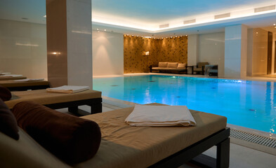 Loungers in lounge area with a thermal swimming pool. Beautiful luxurious interior of a health wellness spa resort