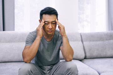 Upset unhappy man squeezing head with hands, writhing in pain, suffering from headache after he spent sleepless night preparing for exams. People, stress, tension and migraine.