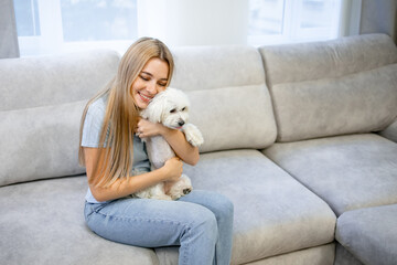 Obraz na płótnie Canvas Young woman relaxing and playing with dog (white maltese) at home. Pet Lover concept