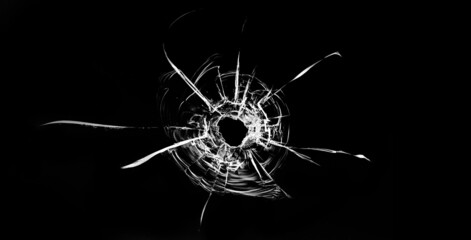 Bullet hole in the glass. Isolated on a black background.