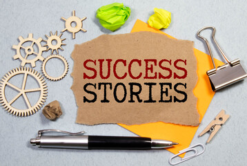 Text success stories written in notepad, Office wood table and red marker from above, concept image