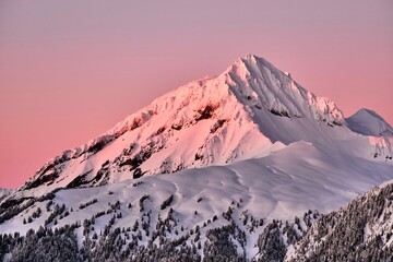 Sunrise in the mountains in winter. Pink glowing sky over snow covered peak. Whistler. British Columbia. Canada
