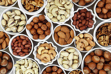 Colorful mix of various nuts: peanut and cashew, hazelnut and almond, pine nuts and walnut; healthy diet snack; vegan food background