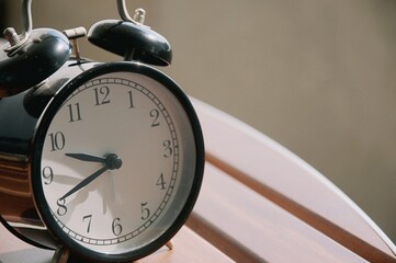Retro alarm clock on table at outdoor patio with sun light blurred  background , interior object for decoration 