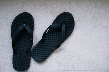 Black Slippers Flip Flops Sandals On The Concrete Texture In Outdoor Natural Light