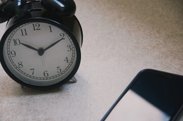Retro alarm clock on table at outdoor patio with sun light blurred  background , interior object...