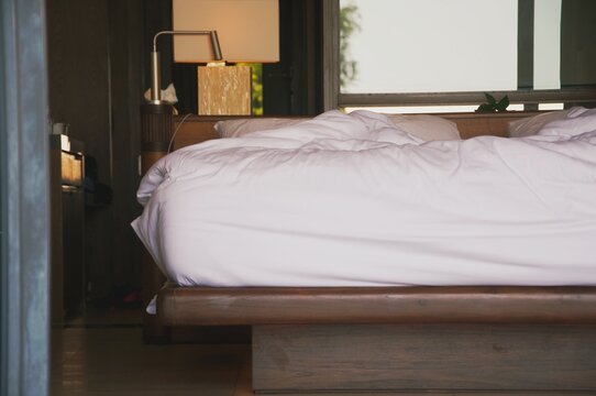 Unmade bed in an hotel room. Early morning, light from the windows.Unmade bed in an hotel room. Early morning, shade. Low light coming from the windows.