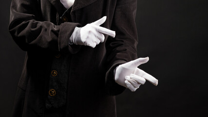 Hand gestures. Point to the side, the show begins. Showman or magician illusionist in white gloves on a black background. - Powered by Adobe