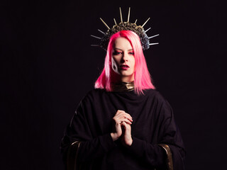A gothic diva with pink hair in a royal image, a crown with roses and rays on her head, hands...