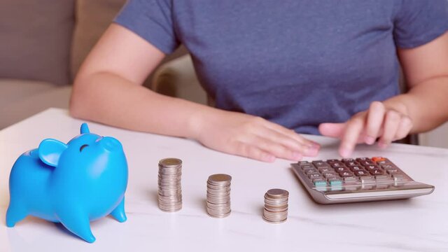 Women using calculators and putting coins in a piggy bank, saving money concept. Future needs loan education or mortgage credit.