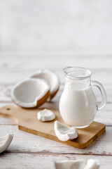 Fototapeta na wymiar A jug of milk next to fresh coconuts