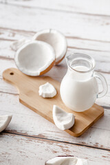 A jug of milk next to fresh coconuts