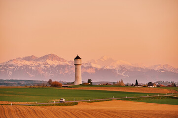 Beautiful swiss landscape with snowy Alps, water tower and spring fields, image taken in canton of...