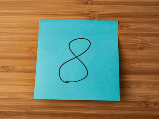 A paper sticker pasted on a wooden surface with the image of the number eight